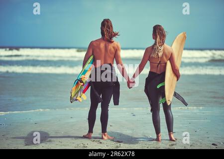 Weniger Zeit für das Surfen im Internet, mehr Zeit für das Surfen auf den Wellen. Rückblick auf ein junges Paar, das auf die perfekte Welle wartet. Stockfoto