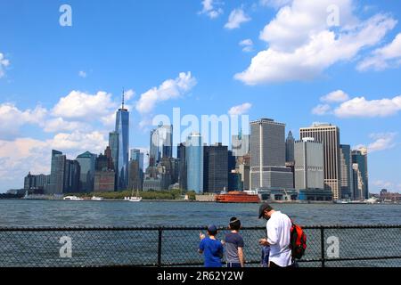 Jüdisch-orthodoxe Familie, Besucher der Governors Island, überblicken den New Yorker Hafen und Manhattans Battery Park am 4. August 2019 in Manhattan, New York Stockfoto