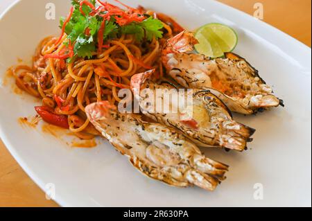 Nudelteller mit Spaghetti-Pasta, gebraten mit Gemüse, Kräuter, würzig, leckere asiatische Nudeln, Meeresfrüchte, gebratene Garnelen auf weißem Pep Stockfoto