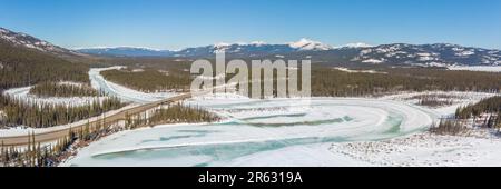 Vogelperspektive auf dem Alaska Highway im Frühling mit Schnee, Eis und gefrorenem See, die im April aufgetaut werden. Stockfoto