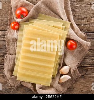 Trockene, ungekochte, gerippte Lasagne-Pasta-Platten, über Kopf fotografiert auf rustikalem Holz Stockfoto