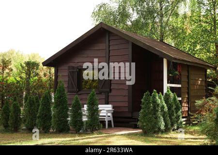 Gemütliches Holzhaus, umgeben von üppiger Natur an sonnigen Tagen Stockfoto