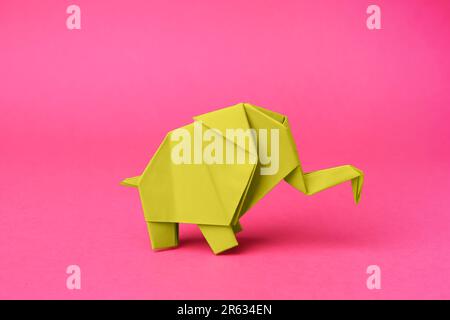 Gelber Papierelefant auf pinkfarbenem Hintergrund. Origami-Kunst Stockfoto