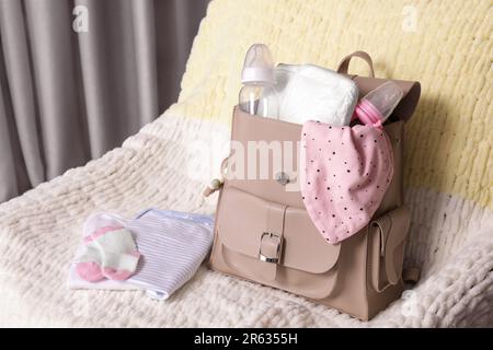 Mutters Tasche mit Babysachen auf einem Sessel im Haus Stockfoto