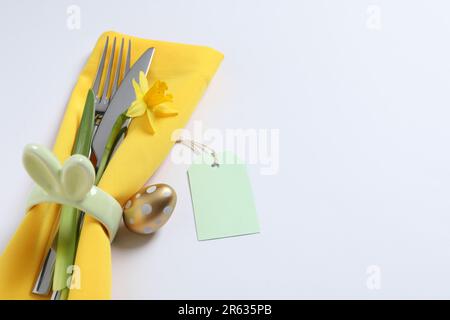 Besteckset, Osterei und Narzisse auf weißem Hintergrund, Platz für Text. Festliche Tischgestaltung Stockfoto