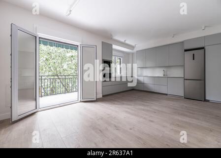 Küche mit großem leeren Raum für Wohnzimmer und Ausgang zur Terrasse mit großem Fenster mit Aluminium- und Glastüren Stockfoto