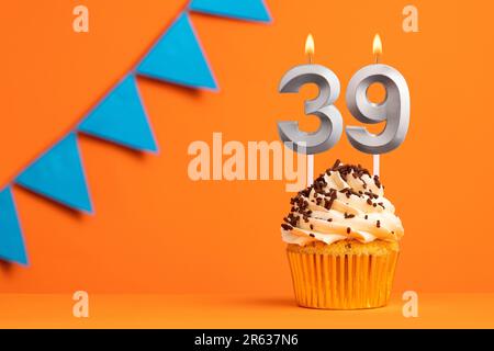 Kerze Nummer 39 - Kuchen zum Geburtstag auf orangefarbenem Hintergrund Stockfoto