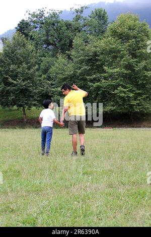 Geschiedener alleinerziehender Vater und 9-jähriger Sohn, braunhaariger Latino, wandern durch die Landschaft und schauen Hand in Hand in Hand in die Zukunft Stockfoto