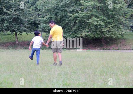 Geschiedener alleinerziehender Vater und 9-jähriger Sohn, braunhaariger Latino, wandern durch die Landschaft und schauen Hand in Hand in Hand in die Zukunft Stockfoto