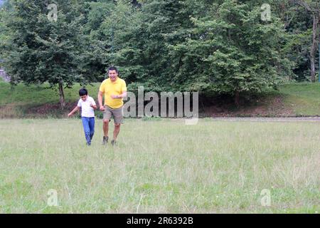 Geschiedener alleinerziehender Vater und 9-jähriger Sohn, braunhaariger Latino, wandern durch die Landschaft und schauen Hand in Hand in Hand in die Zukunft Stockfoto