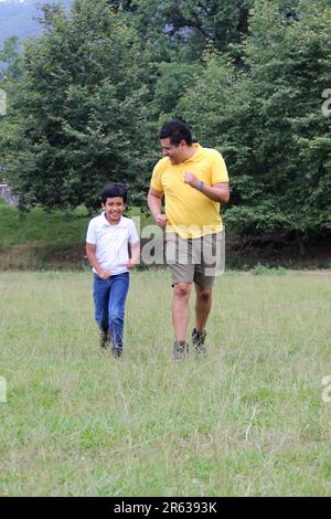 Geschiedener alleinerziehender Vater und 9-jähriger Sohn, braunhaariger Latino, wandern durch die Landschaft und schauen Hand in Hand in Hand in die Zukunft Stockfoto