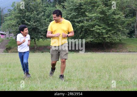 Geschiedener alleinerziehender Vater und 9-jähriger Sohn, braunhaariger Latino, wandern durch die Landschaft und schauen Hand in Hand in Hand in die Zukunft Stockfoto