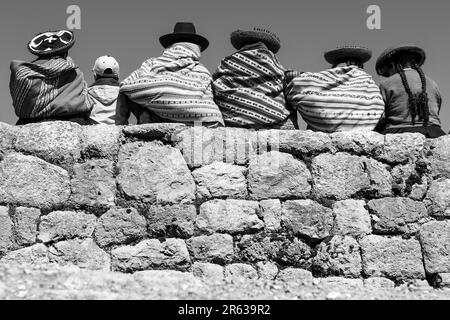 Peruanische Ureinwohner von Quechua auf der Inka-Mauer in Schwarz und Weiß, Chinchero, Cusco, Peru. Stockfoto