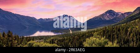 Panoramablick über eine Wildnis in der Nähe von Alaska im Sommer mit hellem rosa WolkenHimmel bei Sonnenuntergang. Malerische Landschaft in Yukon, British Columbia. Stockfoto