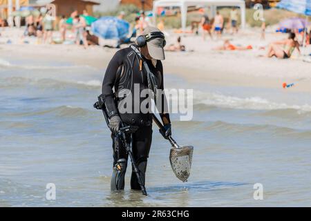 Ukraine, Iron Port - 01. September 2020: Ein Mann mit einem speziellen Gerät und Ausrüstung Metalldetektor auf der Suche nach verlorenen Schmuck und Gold im Meerwasser in der Nähe Stockfoto