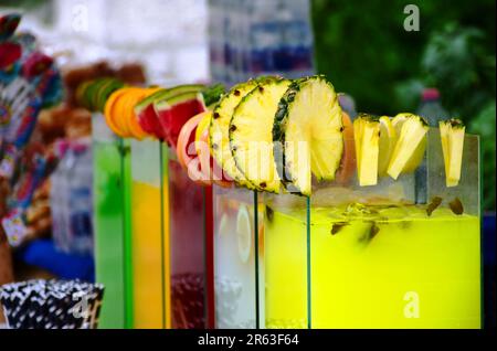 Limonadenstand, Straßenverkäufer, Nahaufnahme. Getränkebehälter mit Glasgeschmack. Fruchtsaft. Ananas-, Grapefruit- und Wassermelonenscheiben am Glasrand Stockfoto