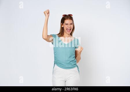 Junge Frau mit erhobenen Händen feiert Erfolg isoliert auf weißem Hintergrund. Stockfoto