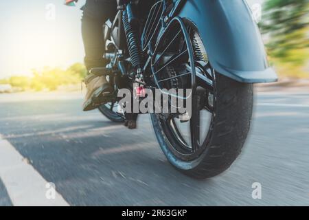 Niedrige Sicht eines Motorradfahrers auf ein Motorrad. Nahaufnahme der Füße eines Motorradfahrers auf seinem Motorrad. Blick aus dem niedrigen Winkel auf einen Motorradfahrer Stockfoto