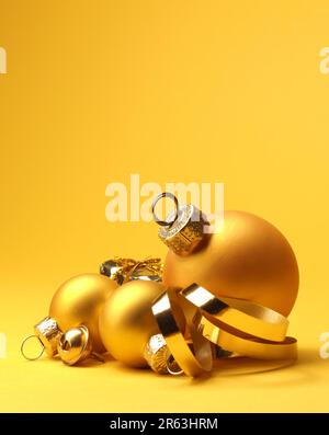Drei goldene vintage Weihnachtskugeln auf einem gelben Hintergrund mit Platz für Ihren Text oder Bild, saisonale Urlaubskonzept Stockfoto