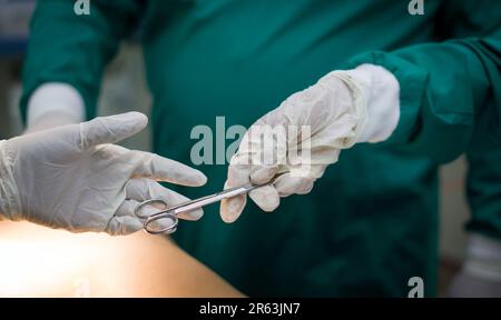 Nahaufnahme im Operationssaal, Assistent gibt während der Operation Instrumente an Chirurgen aus. Stockfoto