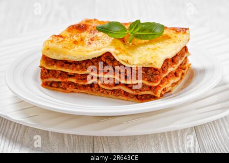 Portion Lasagne al forno, italienische Rinderlasagne mit Rinderhack, Marinara-Sauce, Nudelnudeln und Ricotta-Käse auf weißem Teller auf weißem w Stockfoto