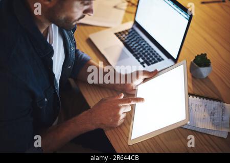 Ich werde nie aufhören, hart zu arbeiten. Ein gutaussehender junger Geschäftsmann, der spät in der Nacht auf seinem Tablet in einem modernen Büro arbeitet. Stockfoto