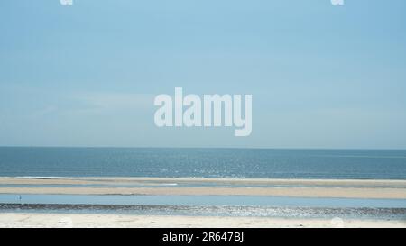 Ruhiger Strand am Tag, weißer Sand und klarer Himmel. Ruhiges Meer mit leerem Strand. Stockfoto