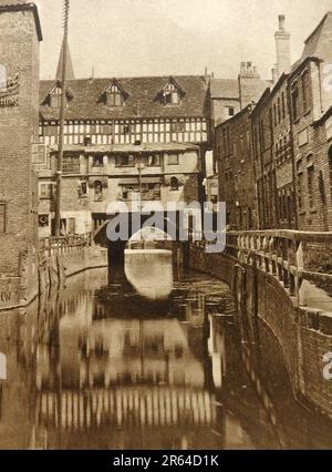 High Bridge in Lincoln England im Jahr 1933. Die High Bridge wurde um 1160.carries an der High Street über dem Fluss Witham in Lincoln erbaut. Es ist die älteste Brücke in Großbritannien, die noch über Gebäude verfügt, die einst ein gemeinsames architektonisches Merkmal von alten Steinbrücken waren. Die vorhandenen Gebäude wurden um 1901 umgebaut. Die alte Brückenkapellbrücke aus dem Jahr 1235 wurde 1549 aufgrund der englischen Reformation nicht genutzt und 1762 abgerissen . Die Öffnung unter der Brücke hat den Spitznamen "Glory Hole" Stockfoto