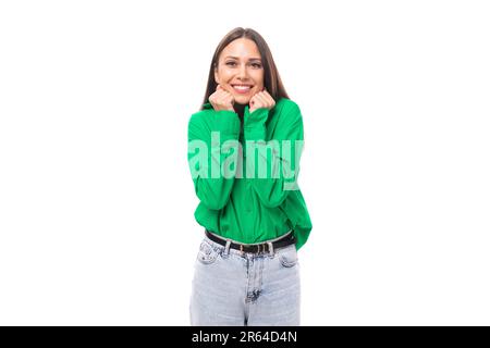 Junge, braunäugige, braunhaarige Frau in einer grünen Bluse freut sich und lächelt Stockfoto