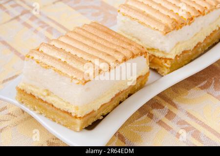 Zwei Scheiben köstlicher und wunderschöner Hüttenkäse als Dessert mit geschlagenem Weiß, Baiser und warmen Farben. Stockfoto