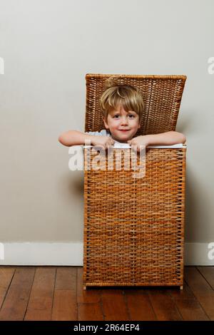 Porträt eines Jungen, der Versteckspiel in einer Holzkiste spielt Stockfoto