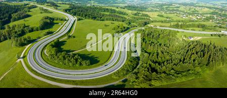 Polen. Panoramablick auf die kurvenreiche Serpentraße von Krakau nach Zakopane, genannt Zakopianka, in der Nähe von Rabka und Chabowka. Luftaufnahme am Morgen im Sommer. Stockfoto