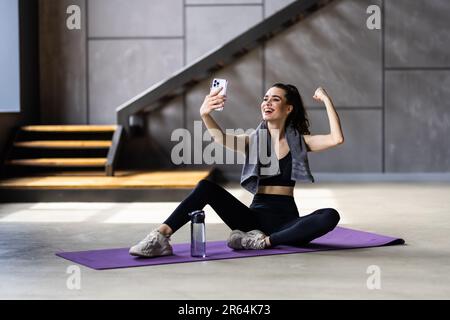 Ganzkörper-Profil Seitenfoto der jungen attraktiven Frau brechen Pause Sit Matte Machen Sie Selfie Handy Sportkleidung nach Hause Stockfoto