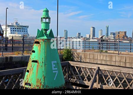 Rostgrüne E7-Navigationboje am Ufer von Birkenhead, die den Mersey-Schifffahrtskanal mit der Skyline von Liverpool markiert Stockfoto