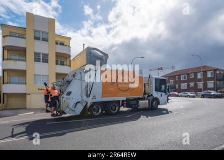 Zwei glückliche Müllsammler winkten und fuhren auf dem Rücksitz eines Lkws in Campbell Parade, North Bondi, Sydney, Australien Stockfoto