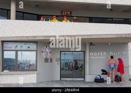 Drei junge Surffrauen beobachten den Strand vom Balkon des North Bondi Surf Life Saving Clubhouse in Sydney, Australien Stockfoto