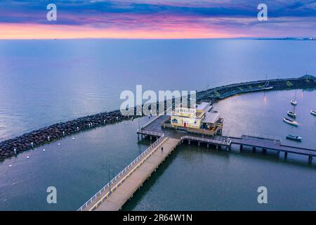 Luftaufnahme ein Pavillon auf einem Pier in einem Wellenbrecher mit einem farbigen Sonnenuntergang in der Ferne am Sandringham in Melbourne, Victoria, Australien. Stockfoto