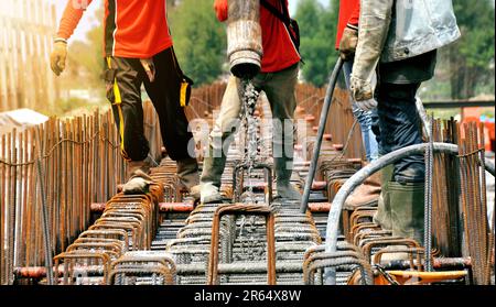 Bauarbeiter, der auf der Baustelle Zement oder Beton mit Pumpenrohr gießt Stockfoto