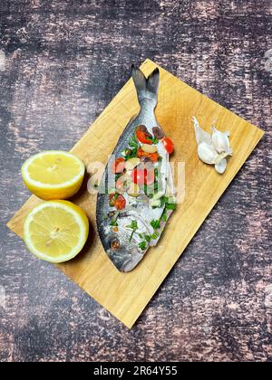 Goldbrasse en Papillote mit Kirschtomaten, Knoblauch und Kapern bereit zum Kochen im Ofen Stockfoto