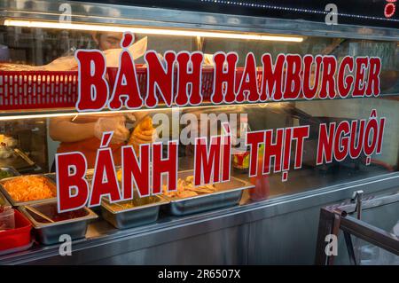 Zwei junge Frauen bereiten traditionelle vietnamesische Banh mi-Sandwiches in einer Bäckerei in Kontum im zentralen Hochland Vietnams zu. Auf dem Schild steht: Aufschnitt Stockfoto