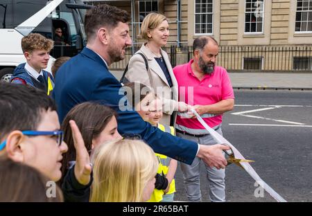 Edinburgh, Schottland, Vereinigtes Königreich, 07. Juni 2023. Straßenbahnen nach Newhaven: Nach 3,5 Jahren ist die Erweiterung der Straßenbahnlinie der Hauptstadt für Fahrgäste geöffnet. Mit der Straßenbahn nach Newhaven fahren Sie 2,91 km weiter, die Leith und Newhaven mit dem aktuellen Ende der Edinburgh Straßenbahnlinie am York Place verbinden, mit 8 neuen Haltestellen. Abbildung: Edinburgh City Council Leader TCmmy Day schneidet das Band mit Grundschulkindern. Kredit: Sally Anderson/Alamy Live News Stockfoto