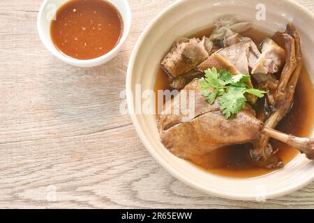 Gekochtes Entenfleisch in schwarzer Sojabohnensuppe in Schüssel, mit scharfer Chilisauce Stockfoto