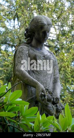 Skulptur einer schönen Frau auf einem Friedhof/Friedhof. Sie hat einen wreth in der Hand. Stockfoto