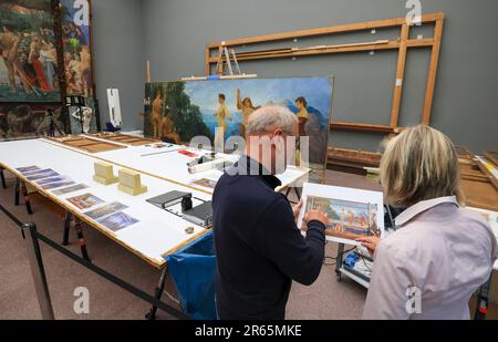 06. Juni 2023, Sachsen, Leipzig: Die Restauratoren Rüdiger Beck und Angelica Hoffmeister-zur Nedden arbeiten öffentlich am Max-Klinger-Gemälde „das Urteil von Paris“ im Museum der Schönen Künste Leipzig, während das Museum geöffnet ist. Die Komposition mit einer Gesamthöhe von 3,70 Metern und einer Länge von etwa 7,50 Metern war einfach zu groß für die Werkstatt und wird daher vor Ort restauriert. Besucher können beobachten, wie Risse in der Leinwand repariert werden, Farben wieder leuchten und Rahmen erneuert werden. Nach dem Sommer wird die Arbeit, die aus mehreren Leinwänden, Holz- und Putzelementen besteht, verschwinden Stockfoto