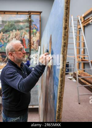 06. Juni 2023, Sachsen, Leipzig: Restaurator Rüdiger Beck überprüft das Max Klinger Gemälde "das Urteil von Paris" im Museum der Schönen Künste Leipzig auf Schäden. Die Komposition mit einer Gesamthöhe von 3,70 Metern und einer Länge von etwa 7,50 Metern war einfach zu groß für die Werkstatt und wird daher vor Ort restauriert. Besucher können beobachten, wie Risse in der Leinwand repariert werden, Farben wieder leuchten und Rahmen erneuert werden. Nach dem Sommer werden die Arbeiten, die aus mehreren Leinwänden, Holz und Putz bestehen, installiert. Foto: Jan Woitas/dpa Stockfoto