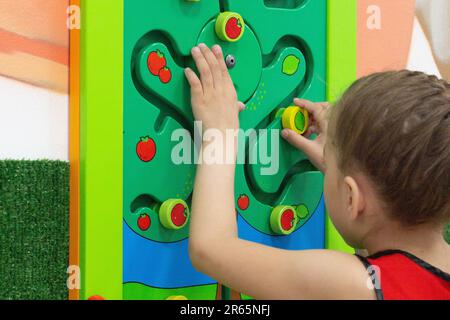 Kaukasisches kleines Mädchen von 6 Jahren, das mit hölzernen Labirints im Spielzentrum im Inneren spielt Stockfoto