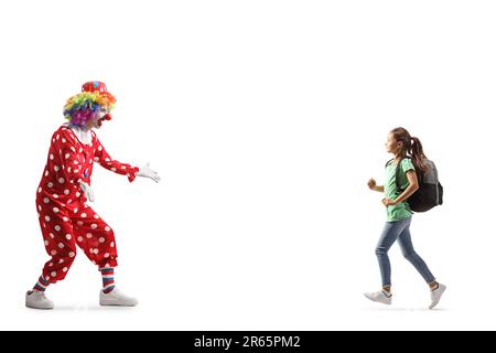 Ein Mädchen mit einem Rucksack läuft auf einen Clown zu, isoliert auf weißem Hintergrund Stockfoto