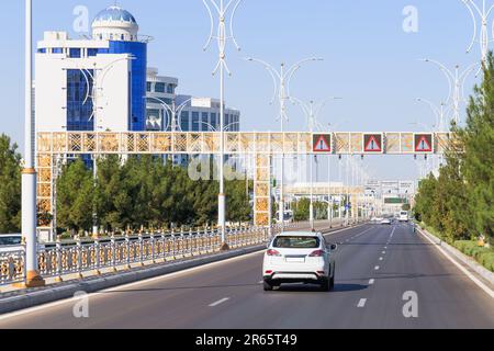 Urbanes Stadtbild des Stadtzentrums von Ashgabat mit breiter Autobahn und leichtem Verkehr. Hohe weiße Marmorgebäude an den Seiten. Hauptstadt Turkmenistans. Zentrum A Stockfoto