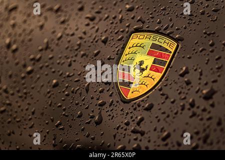 Masi, Italien, 7. juni 2023: Nahaufnahme eines schwarzen Autos mit dem berühmten Porsche-Emblem und Wassertropfen. Stockfoto