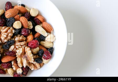 Bild mit einer halben Schüssel gemischter Nüsse und getrockneten Früchten, bestehend aus Mandeln, Walnüssen, Haselnüssen, Kaschu-Nüssen, Rosinen und Cranbeeren. Gesundes Essen Stockfoto